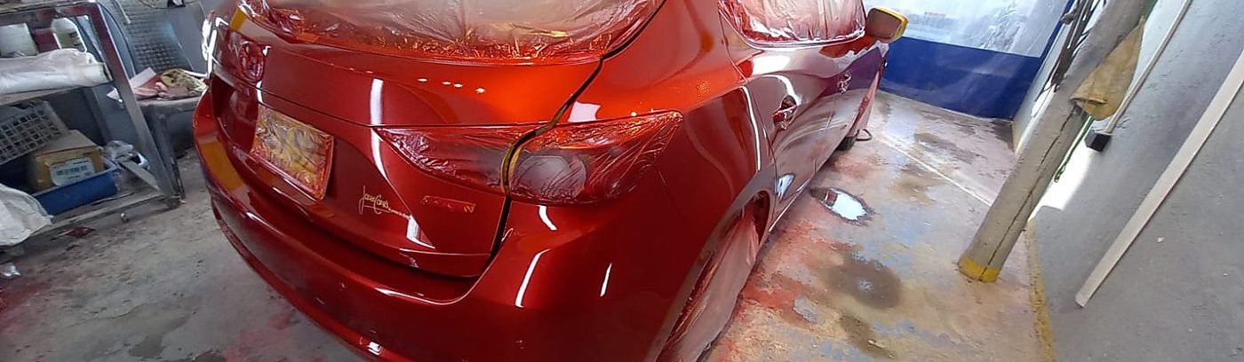 Carro plateado en proceso de pintura en el taller de Auto Man DC