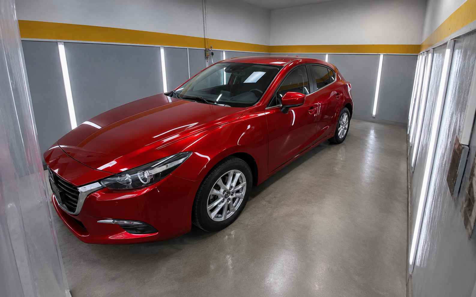 Panel trasero de un Mazda 3 rojo con la pintura pulida y reflejo limpio
